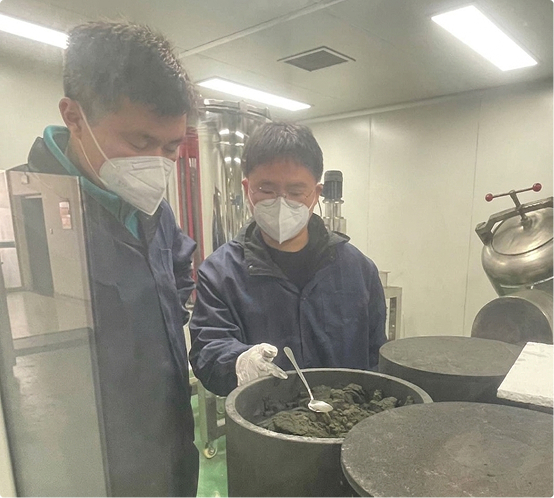 Two UNIGRID team members in masks and gloves making NCO cathode material in the lab